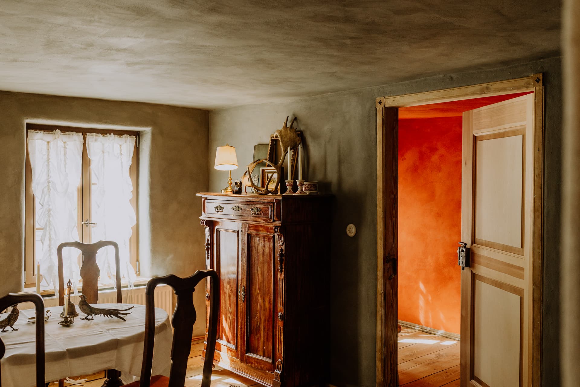 Speisezimmer im Obergeschoss mit rundem Esstisch, weißer Leinendecke, Biedermeierstühlen und antikem Vertiko