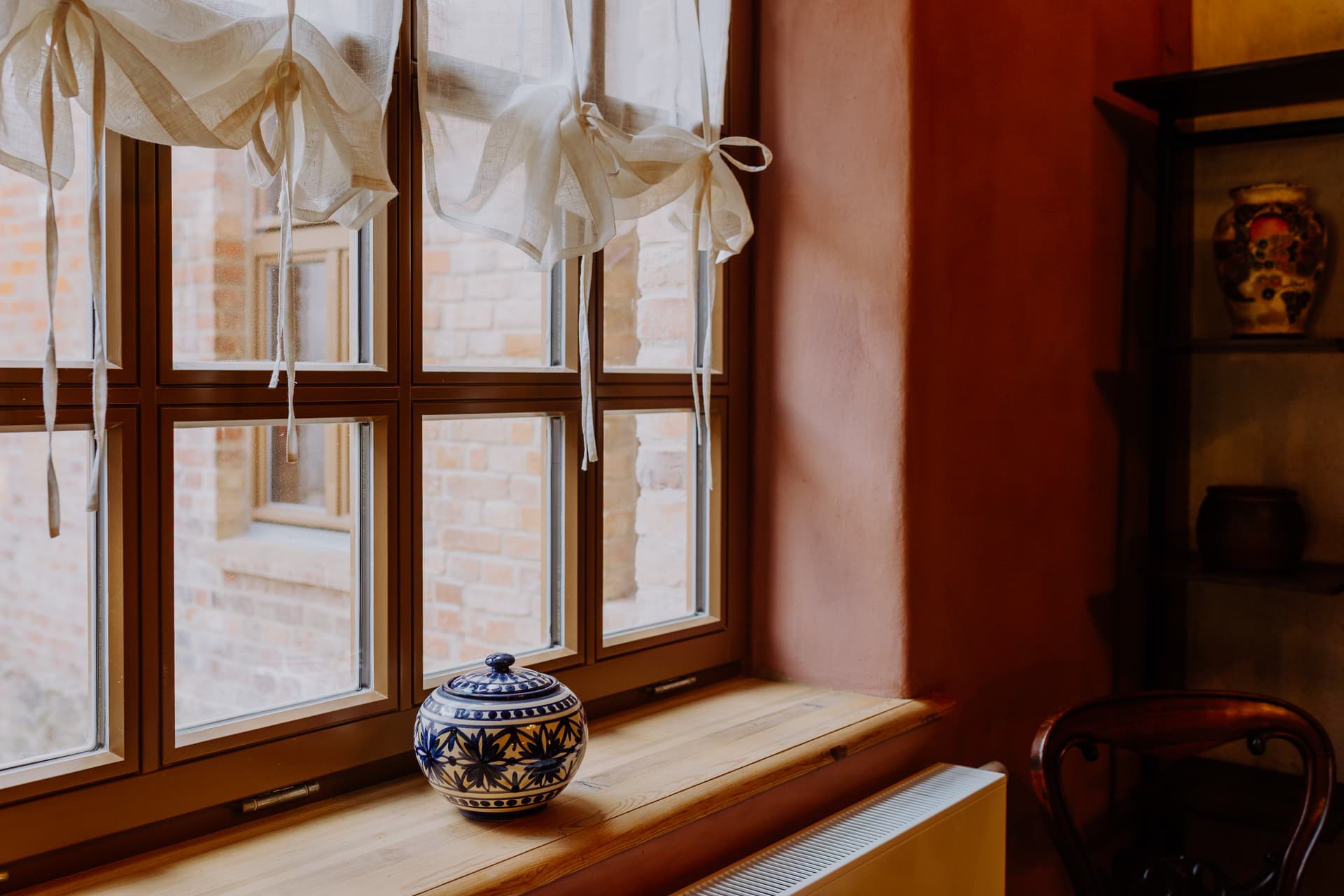 Fensternische im Schlafzimmer 1 mit blau-weißer Keramik, Leinengardinen und Blick in den Hof