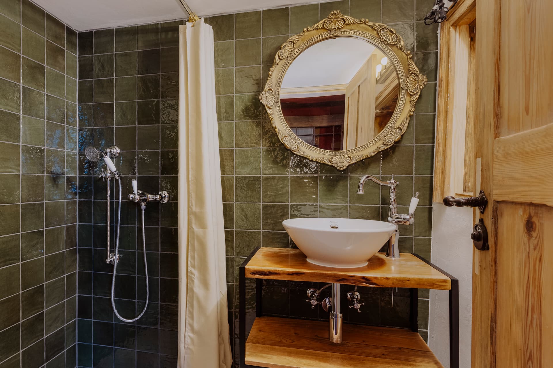 Duschbad mit waldgrünen Fliesen, Walk-In-Dusche, Holzkonsole mit Aufsatzwaschbecken und prunkvollem Goldspiegel